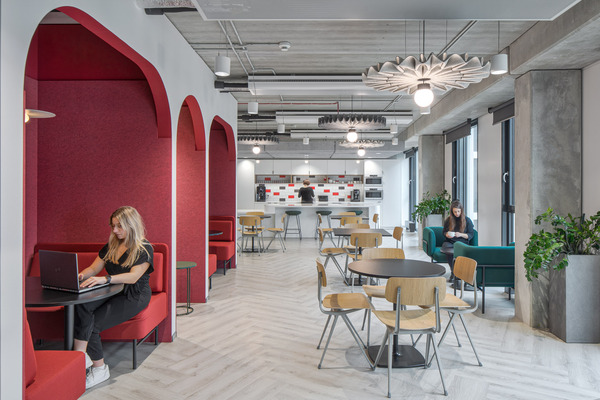 corporate interiors workplace with woman sitting in a red booth