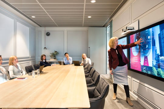 People in meeting room with touchscreens. 