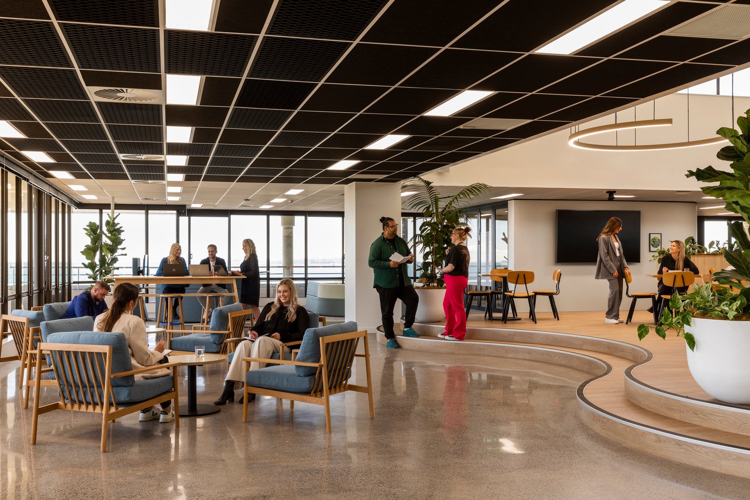 Vibrant social hub area with variety of chairs and desks, surrounded by greenery 