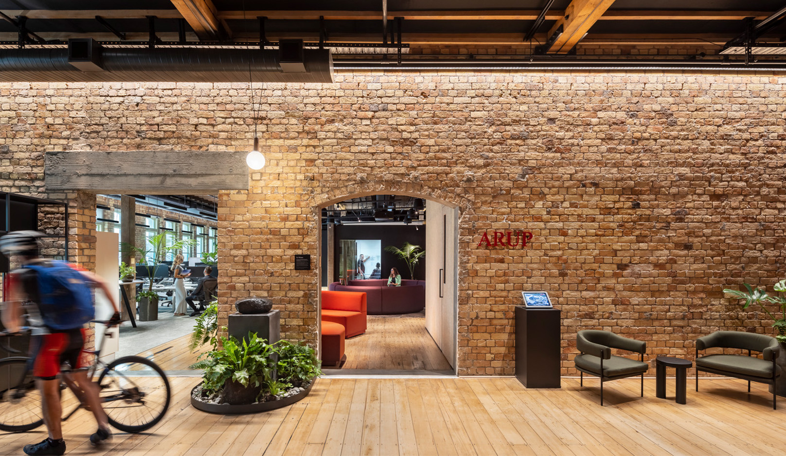 Sustainable office design with brick wall and person with a bike. 