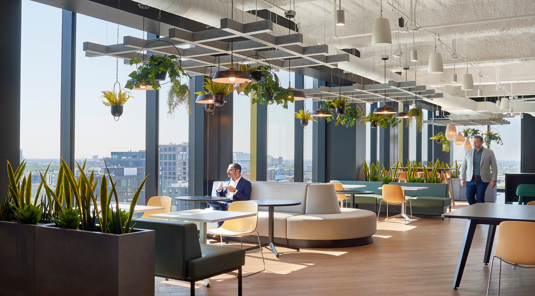 Indoor office with plants and man looking out window. 