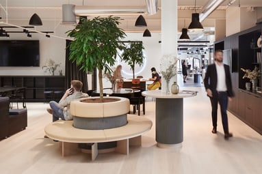 Man walks through open meeting space in Unispace's London office with natural light and greenery all around