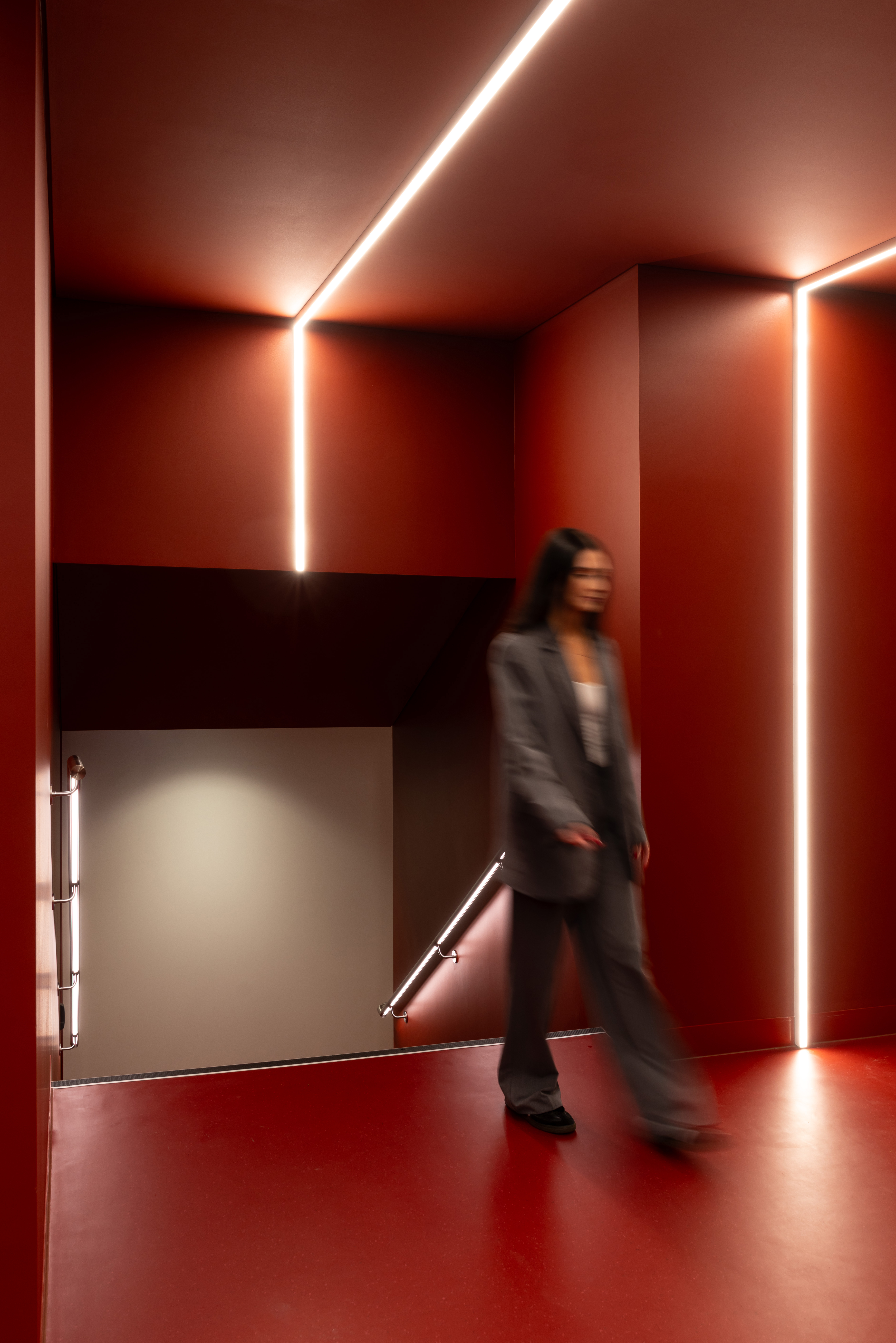 Entrance to end of trip facilities with feature lighting and a deep red colour palette 