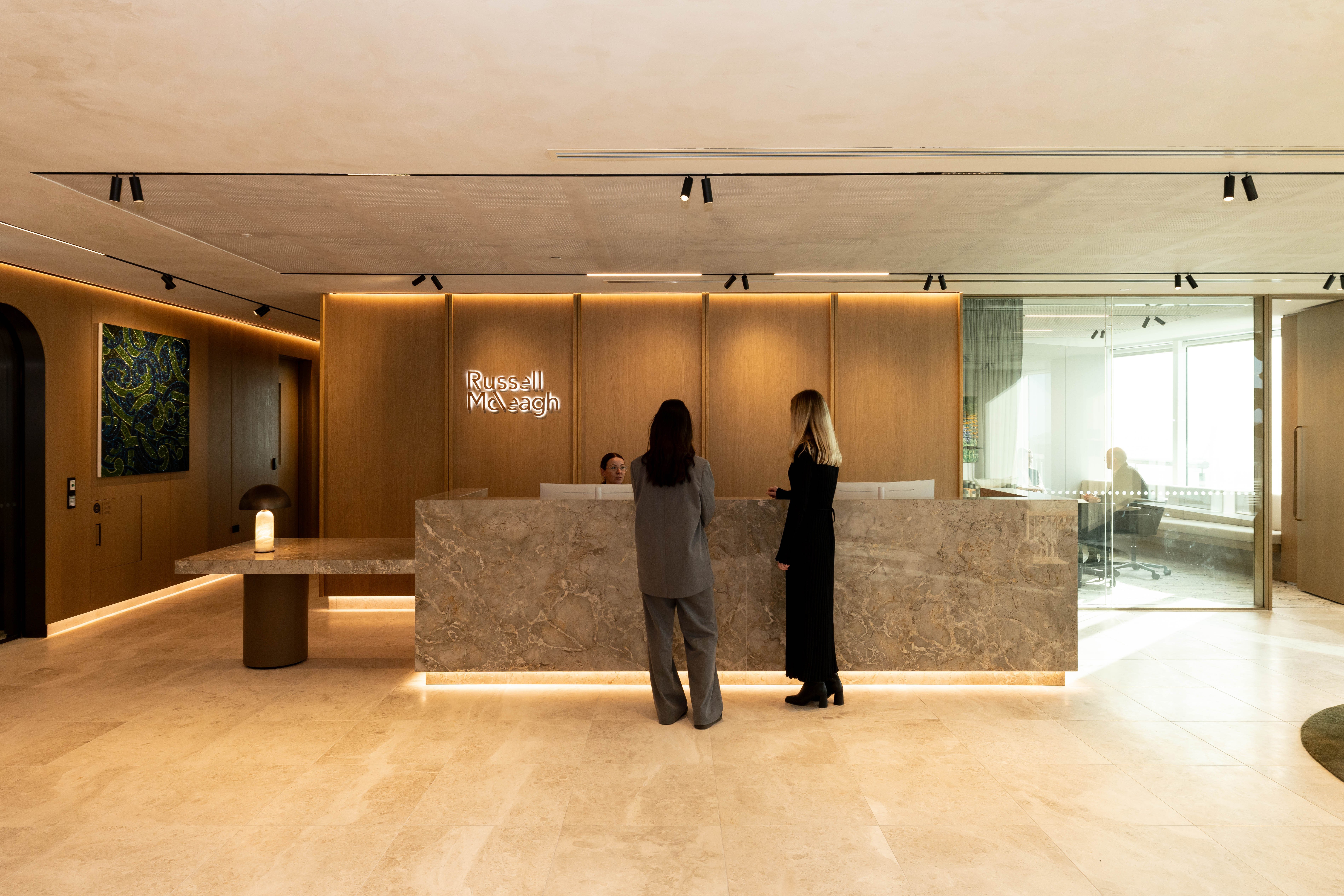 Client entrance and reception at Russell McVeagh's Wellington office with two people standing in front of reception desk