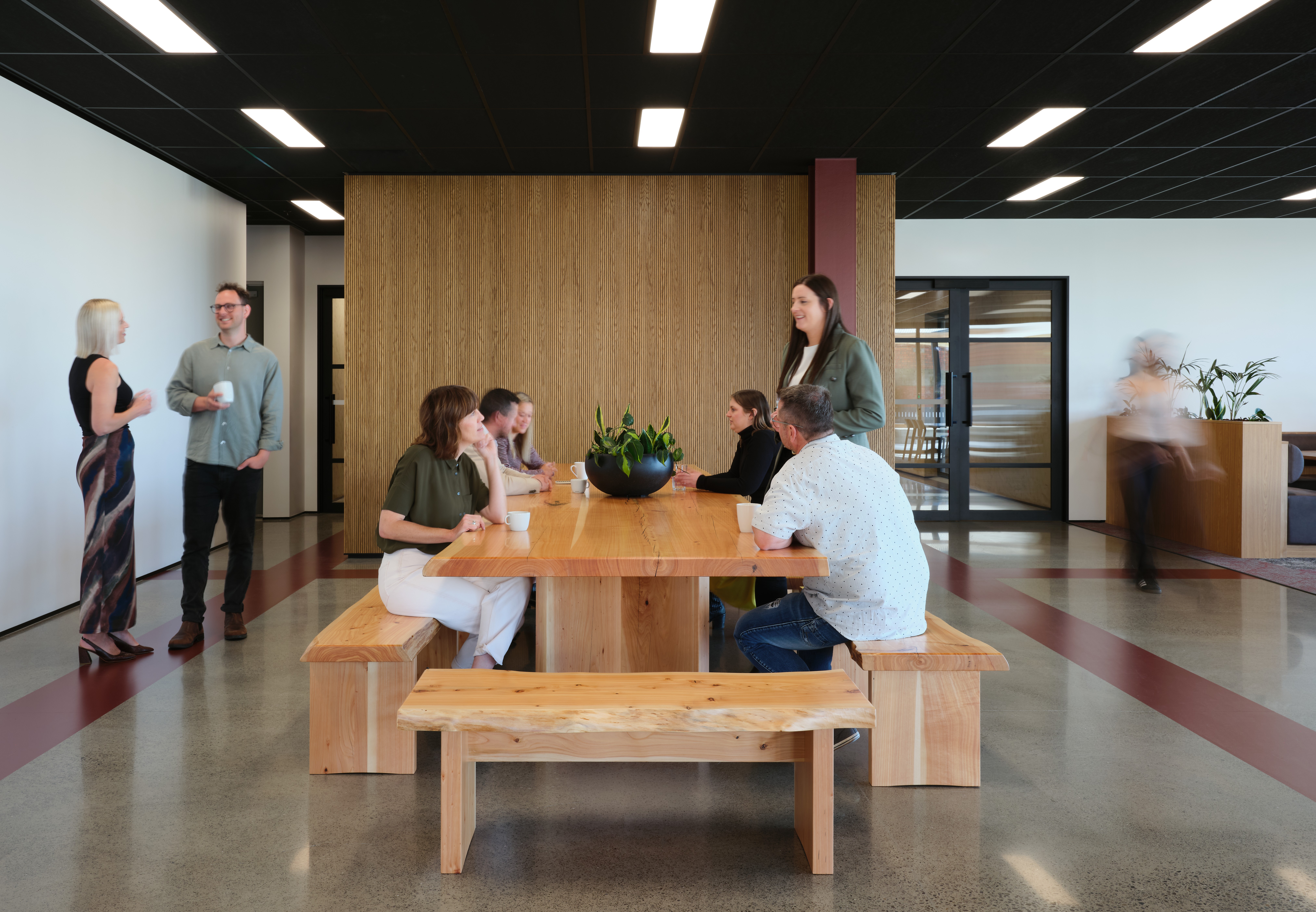 Timber kitchen table with employees gathered around and chatting