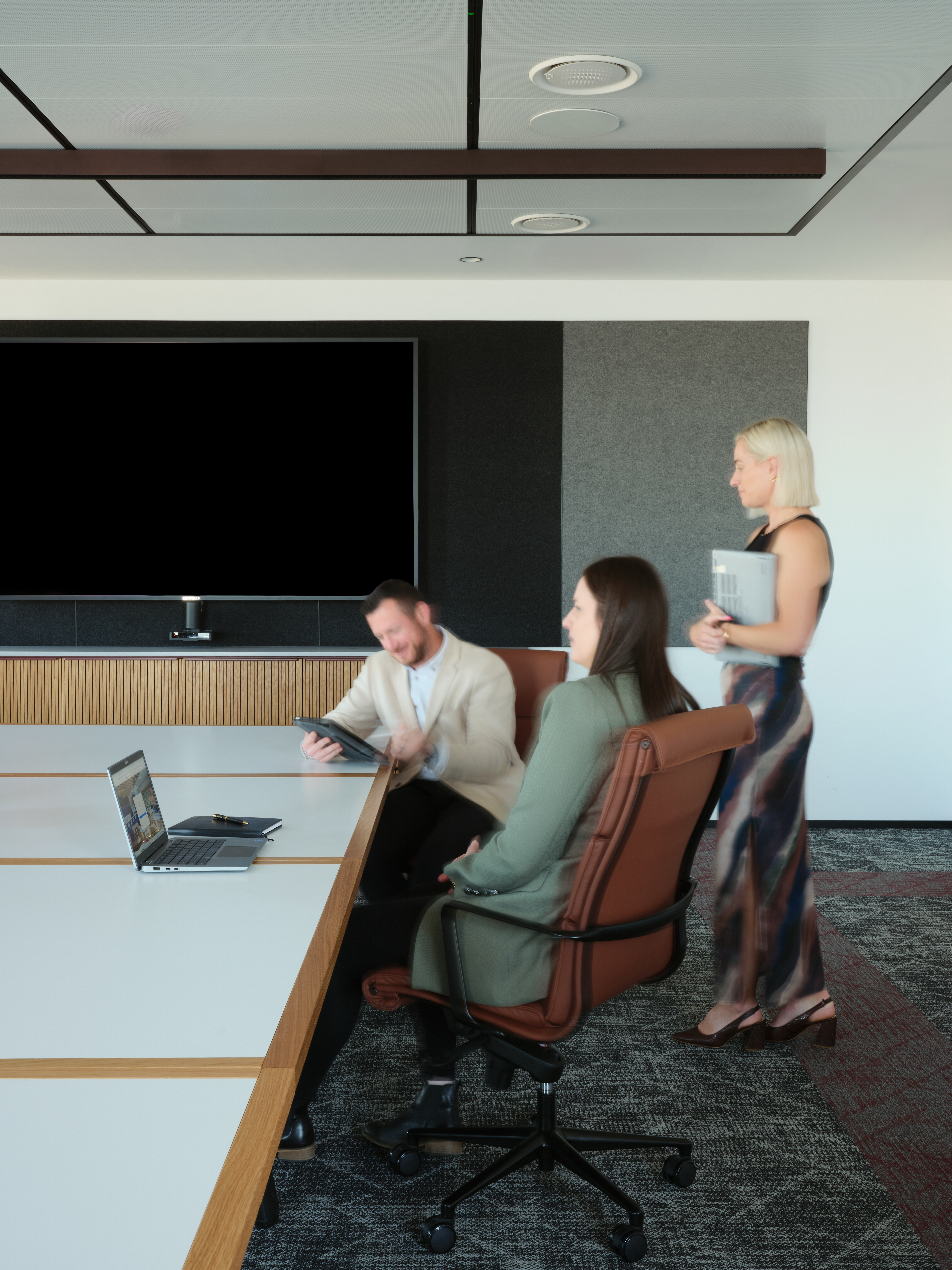 Employees sat in boardroom with laptops