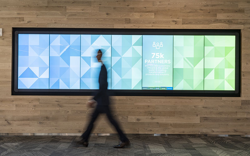 Man walking by wall with screens that shows statistics